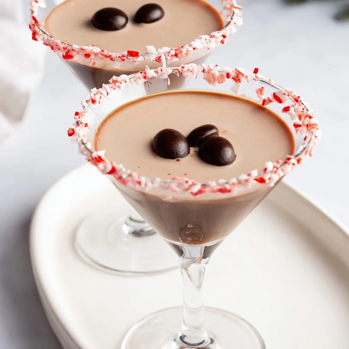 Festive chocolate peppermint rimmed glasses filled with cold Peppermint Espresso Martinis, ready to serve.