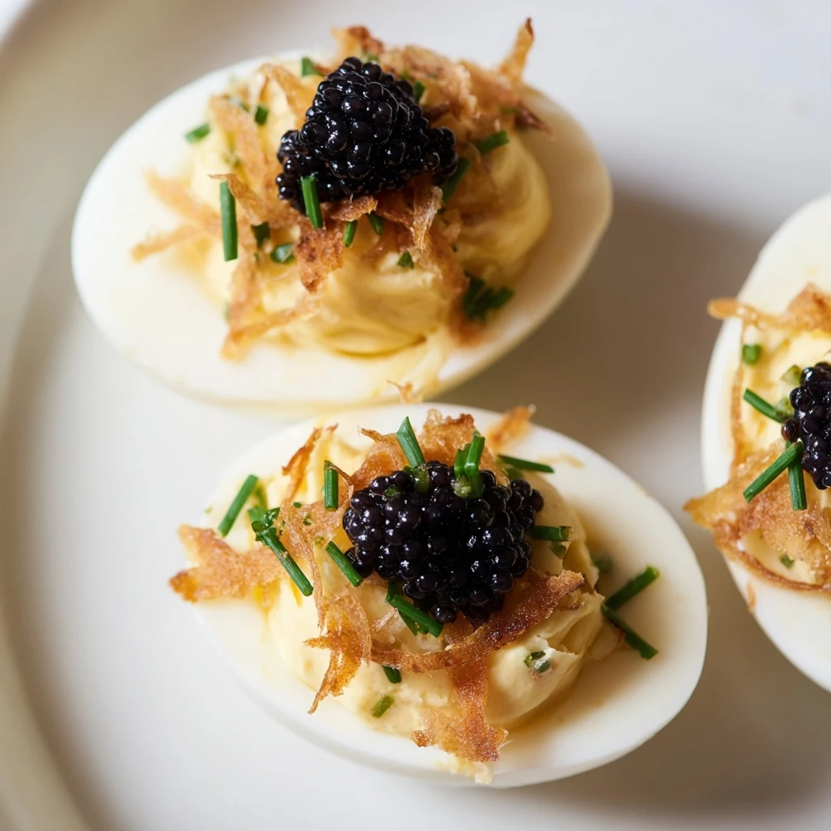 Creamy deviled eggs, delicately piped, topped with salty caviar and crispy shallots, ready to eat.