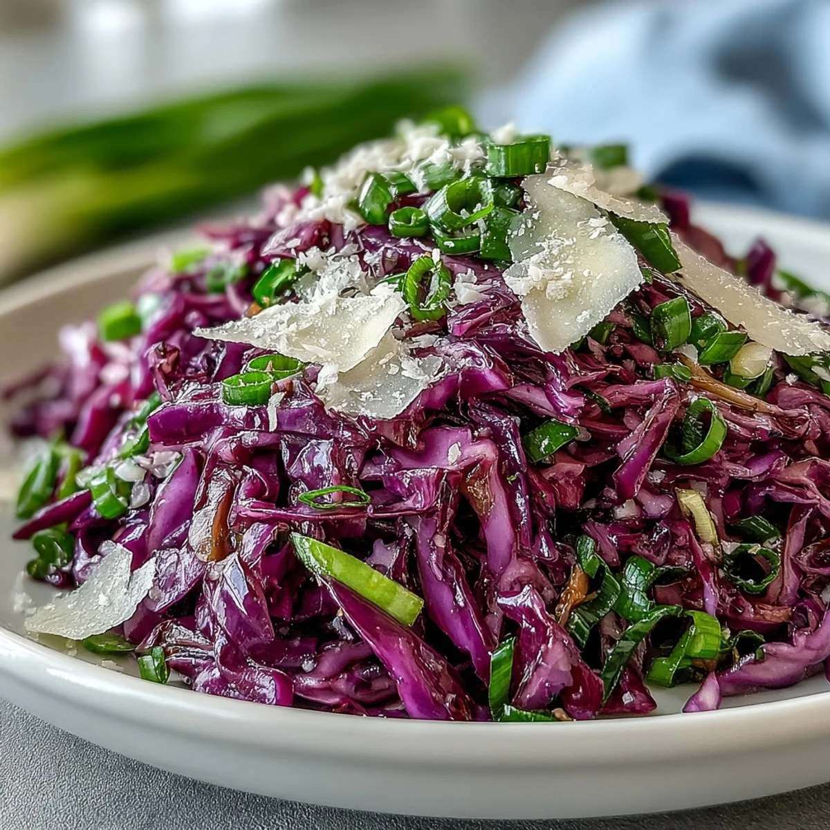 Shredded Red Cabbage Coleslaw With Apple and Parmesan tossed in a tangy vinaigrette on a rustic table.