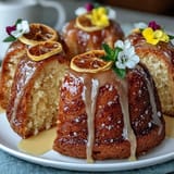 Zesty lemon cake drizzled with citrus syrup and adorned with colorful edible flowers for special occasions.