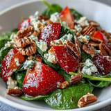 Bright and refreshing strawberry spinach salad with tangy goat cheese, crunchy toasted nuts, and a sweet balsamic dressing, perfect for summer gatherings.