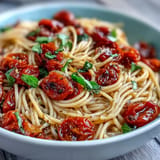 Cherry Tomato Confit Pasta with Garlic Oil, glistening tomatoes over spaghetti.