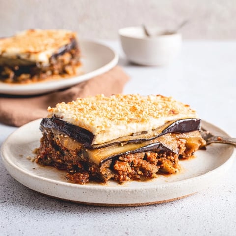 Golden-brown moussaka with layers of beef and eggplant, topped with creamy béchamel, ready to serve.
