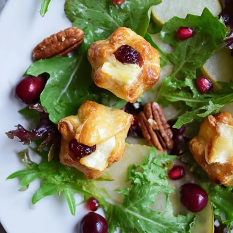 Golden-baked cranberry and brie flower bites sit atop a fresh salad, ready to eat.