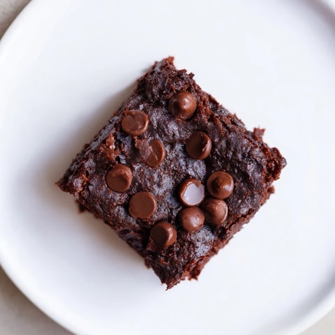 Warm, fudgy Greek Yogurt Brownies with melted chocolate chips, ready to cut into squares for serving.