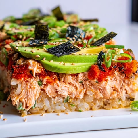 Warm and inviting, this sushi bake casserole shows flaked salmon and creamy avocado topping rice.