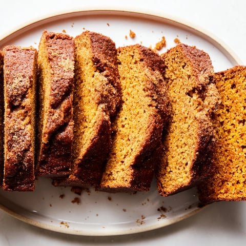 Freshly baked Pumpkin Bread Loaf cooling on a wire rack with warm spices rising from the golden crust.