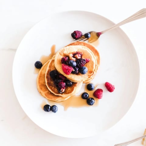 Warm golden-brown banana pancakes sizzling gently in a skillet, ready to flip with a soft, fluffy texture.