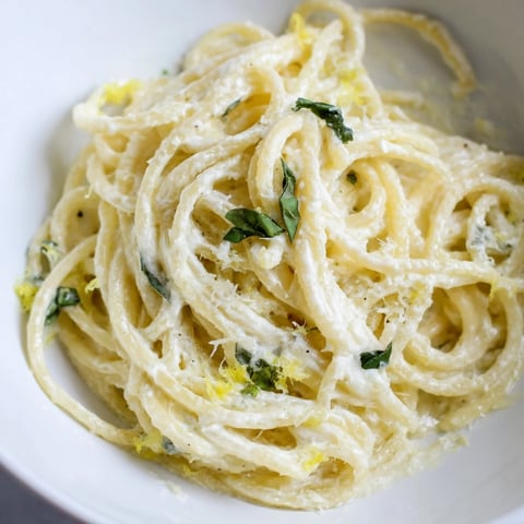 Steaming spaghetti coated in creamy ricotta and bright lemon zest, garnished with fresh basil for a zesty Lemon Ricotta Pasta dish.