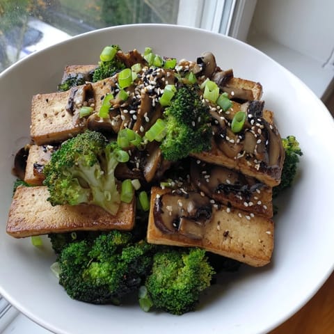A close-up view of perfectly seared Sautéed Tofu Steak, complemented by tender broccoli and a rich sauce.
