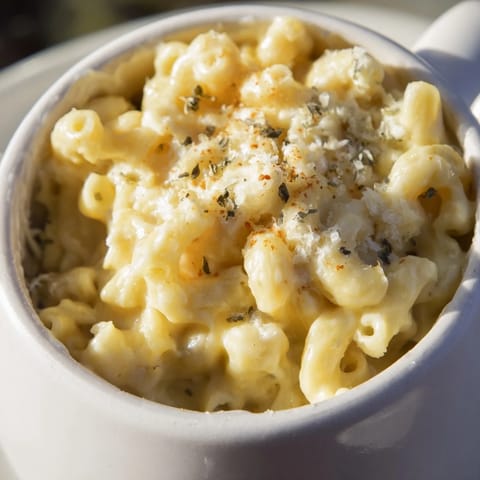 A close-up of a bubbling mug mac & cheese, ready to eat, with a sprinkle of paprika on top.