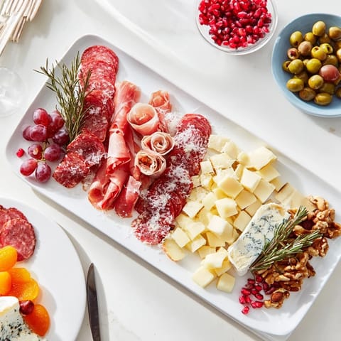 This beautiful Winter Forest Charcuterie Scene features artfully arranged meats and cheeses, ready to eat alongside garnishes.