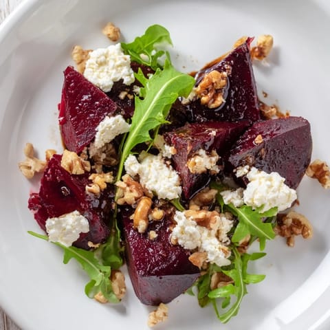 A close-up of the roasted beet goat cheese salad drizzled with glossy balsamic vinaigrette and topped with chopped walnuts.  