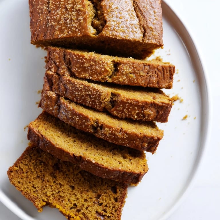 A thick slice of moist Pumpkin Bread Loaf with chocolate chips, paired with a steaming mug of coffee.