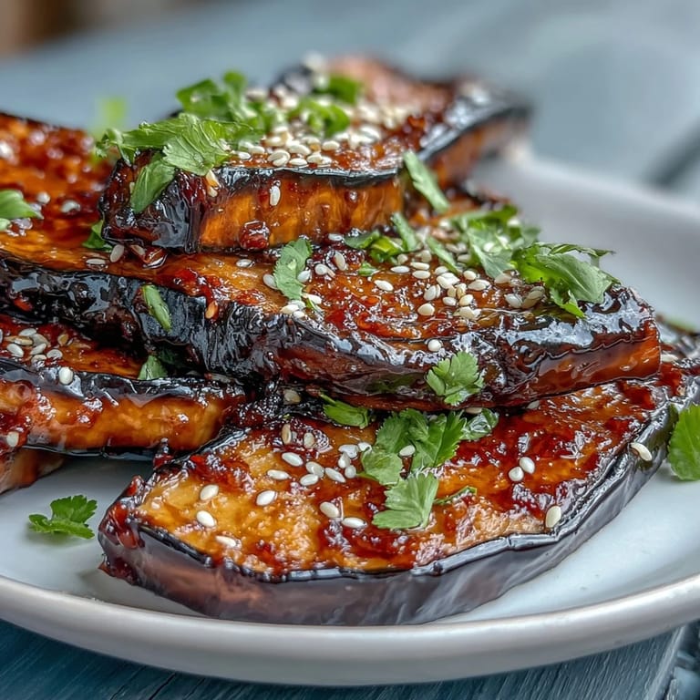 Golden miso-glazed eggplant steaks with rich umami flavor, served on a platter and garnished with sliced green onions and fresh cilantro.  