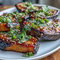 Savory miso-glazed eggplant steaks roasted to tender perfection, with a glossy caramelized topping and a sprinkle of sesame seeds for crunch.  